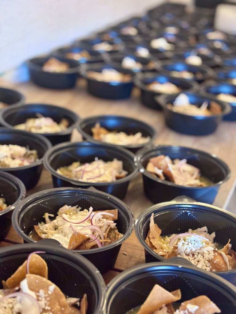 Multiple black bowls with rice, sliced pink ginger, and crispy wonton chips arranged in rows on a light surface