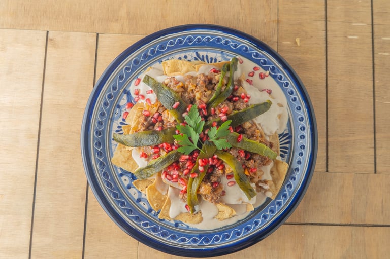 Traditional chile en nogada on blue and white decorative plate topped with garnishes