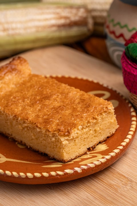 Golden cinnamon sugar loaf cake on a decorative clay plate with fresh corn in the background