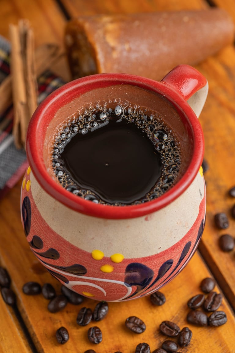 Red and white decorative mug filled with black coffee surrounded by coffee beans on a wooden surface